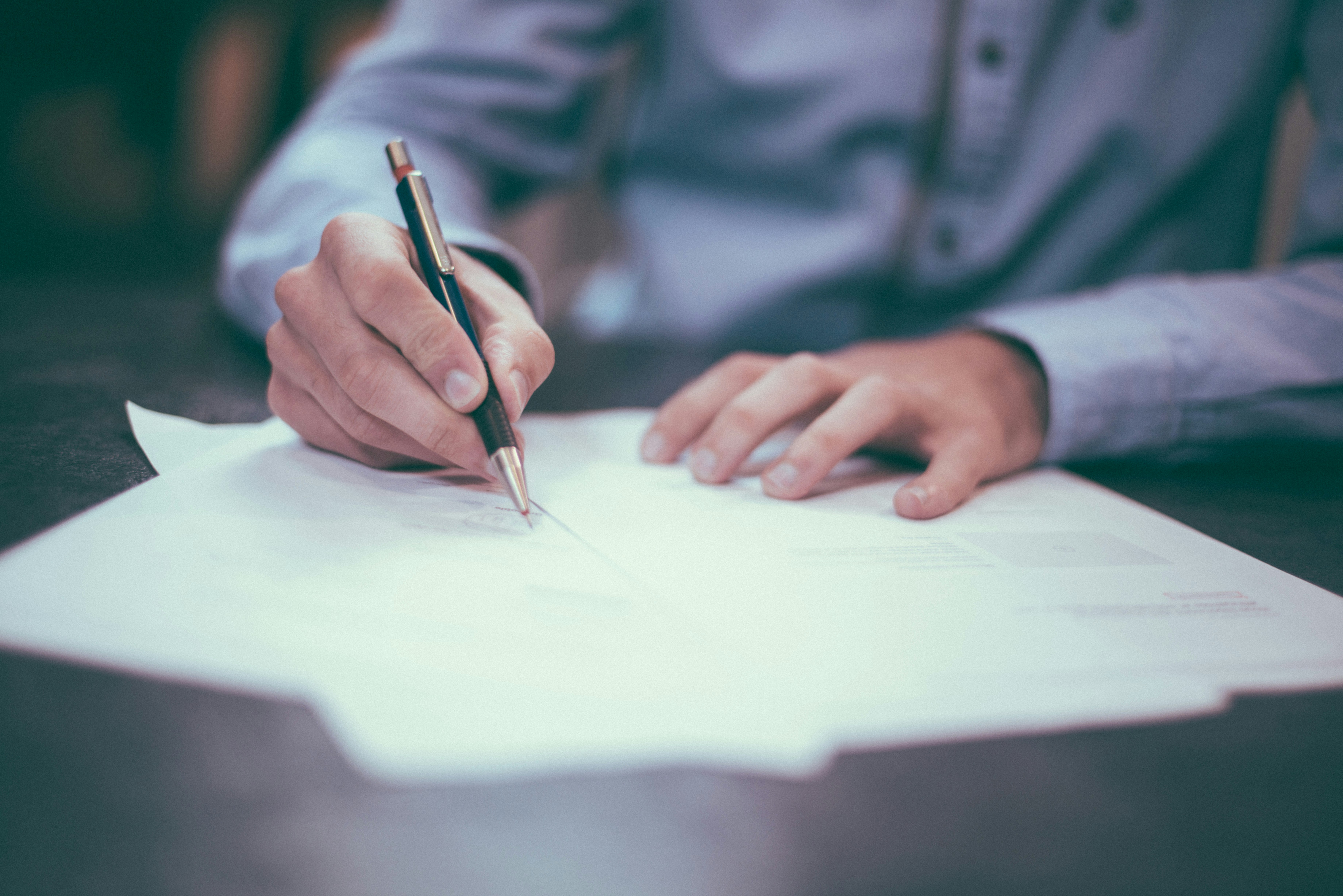 A Person Writes on a Piece of Paper Using a Pen